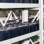 Rows of industrial batteries connected with cables in a storage facility