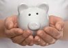 Hands holding a white ceramic piggy bank