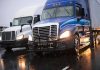 Two trucks driving on a wet road.