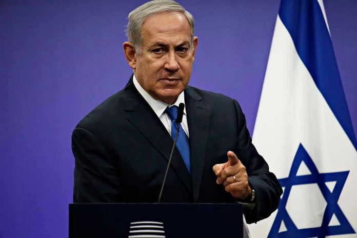 Man in suit giving speech in front of Israeli flag.