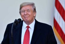 Trump Stadium BOMBSHELL — NFL in Uproar Man in suit and tie speaking at podium.