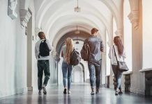AI Cheating Meltdown Hits Top Universities Four students walking in a corridor together.