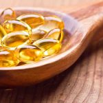 Golden omega 3 capsules in a wooden spoon