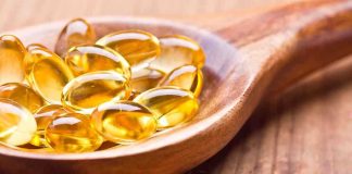 Golden omega 3 capsules in a wooden spoon
