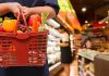 Person holding a basket filled with colorful vegetables in a supermarket