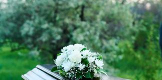 Coffin with white flowers outdoors in green surroundings.