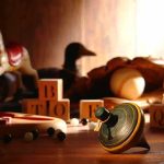 Stunning Shift: Toys Aren’t Just for Kids Anymore A wooden spinning top surrounded by vintage toys and colorful blocks