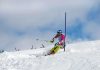 Athlete skiing down a snowy slope around a slalom pole