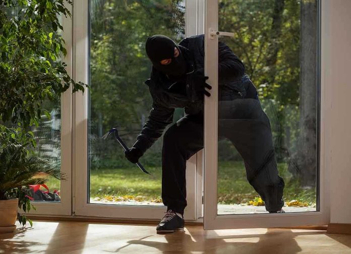 shutterstock_167973983.jpg A burglar in dark clothing entering a house through a glass door