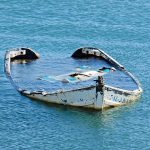 An abandoned boat partially submerged in calm water