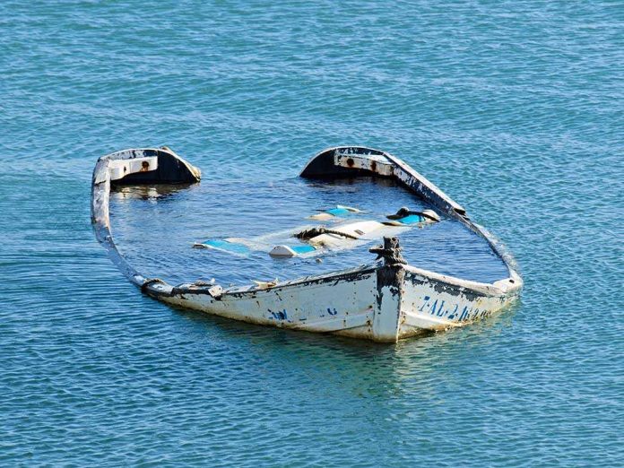 An abandoned boat partially submerged in calm water