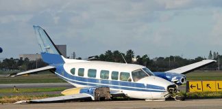 Damaged blue and white small airplane on an airport runway