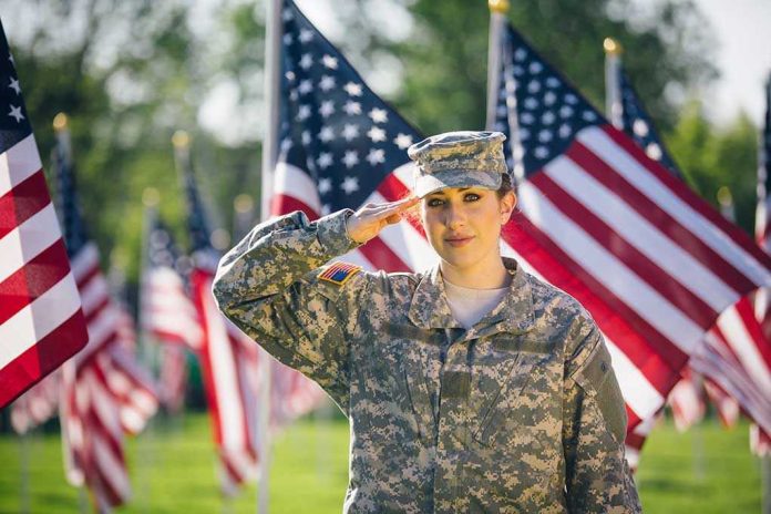 Soldier saluting in front of American flags outdoors.