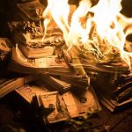 Stacks of hundred dollar bills burning in flames.