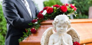 Statue of angel in front of coffin with roses.