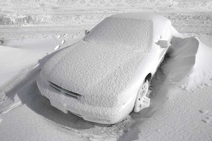 A car completely covered in snow, surrounded by a winter landscape