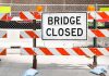 A Bridge Closed sign surrounded by safety barriers and fencing