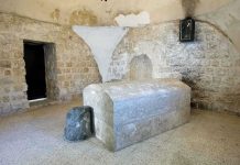 Interior of a historical site featuring a stone tomb and ancient walls