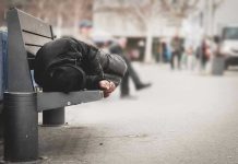 Person sleeping on a bench in a public area.