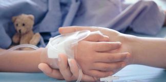 Childs hand with IV, held by adult.