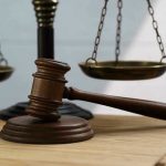 Gavel and scales of justice on wooden table.