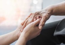 Young hands holding an elderly persons hand.