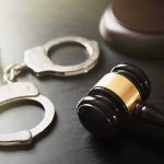 Handcuffs and judges gavel on the table.