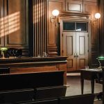 Plea Deal Triggers VIOLENT Courthouse Evacuation Empty courtroom with wooden interior and green lamps.