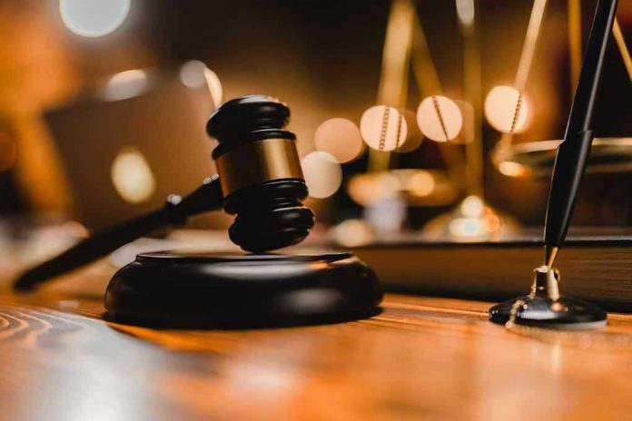 Gavel on wooden table with scales in background.
