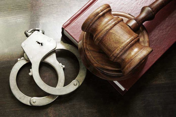 Handcuffs beside a gavel on a book.