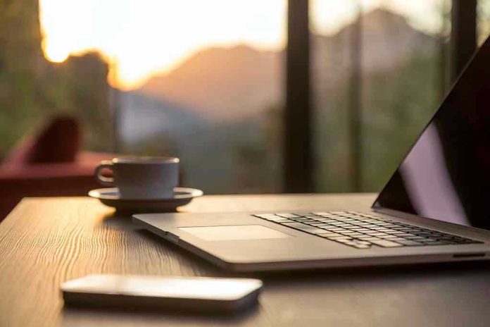 Laptop, coffee cup, and phone on wooden table.