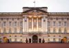 Front view of Buckingham Palace with illuminated facade and British flag