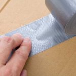 FedEx Demands Billion-Dollar Trump REFUND A hand applying duct tape to a cardboard box