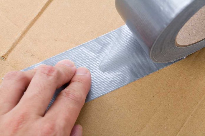 shutterstock_16177381.jpg A hand applying duct tape to a cardboard box