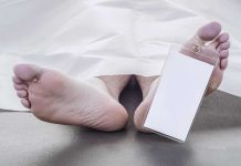 Feet of a deceased person covered by a white sheet with an identification tag