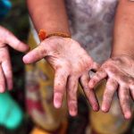 Two childrens hands raised, showing dirt and grime from outdoor play