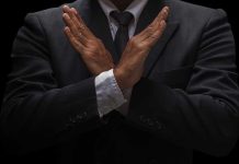 A man in a suit crossing his arms in a gesture of refusal or rejection