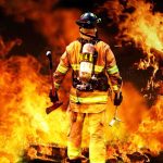 Terminated Fire Chief SUES LA City Firefighter standing in front of a large fire, equipped with tools