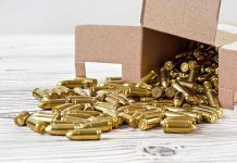 Box of brass bullets spilled on wooden surface.
