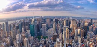 Aerial view of city with skyscrapers and cloudy sky.