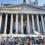 Courthouse facade with media crews setting up outside.