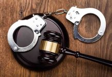 Gavel and handcuffs on wooden surface.