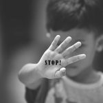 Child holding up hand with STOP written on palm.