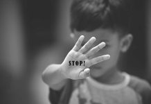 Child holding up hand with STOP written on palm.