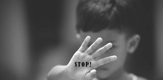 Child holding up hand with STOP written on palm.