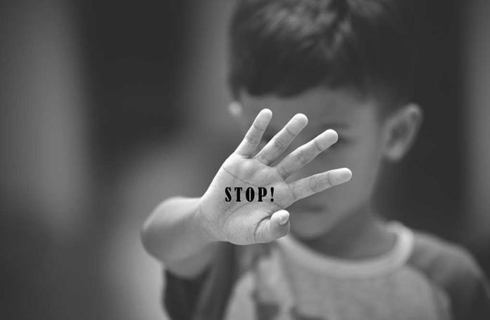 Child holding up hand with STOP written on palm.