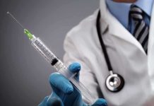 A doctor holding a syringe with a stethoscope around their neck