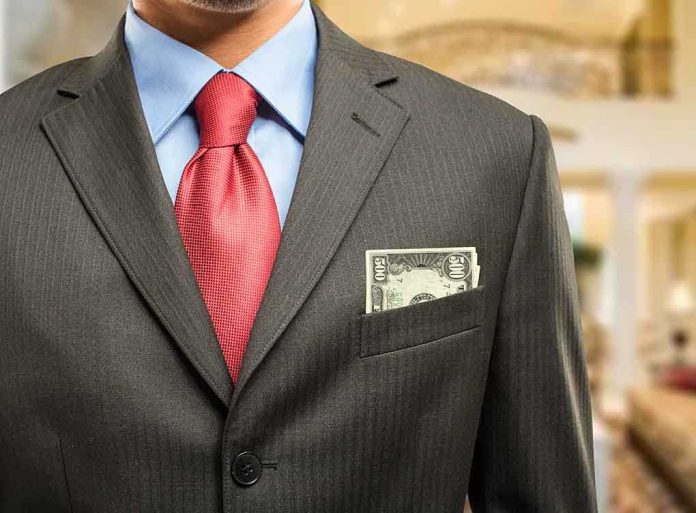 Man in a suit with a red tie and money peeking from his pocket