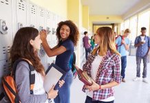 Three high school students interacting near lockers in a hallway