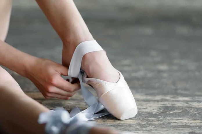 Ballet dancer tying pointe shoes in a studio